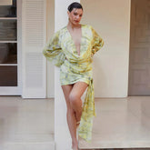 Woman wearing a yellow and green patterned dress standing indoors.